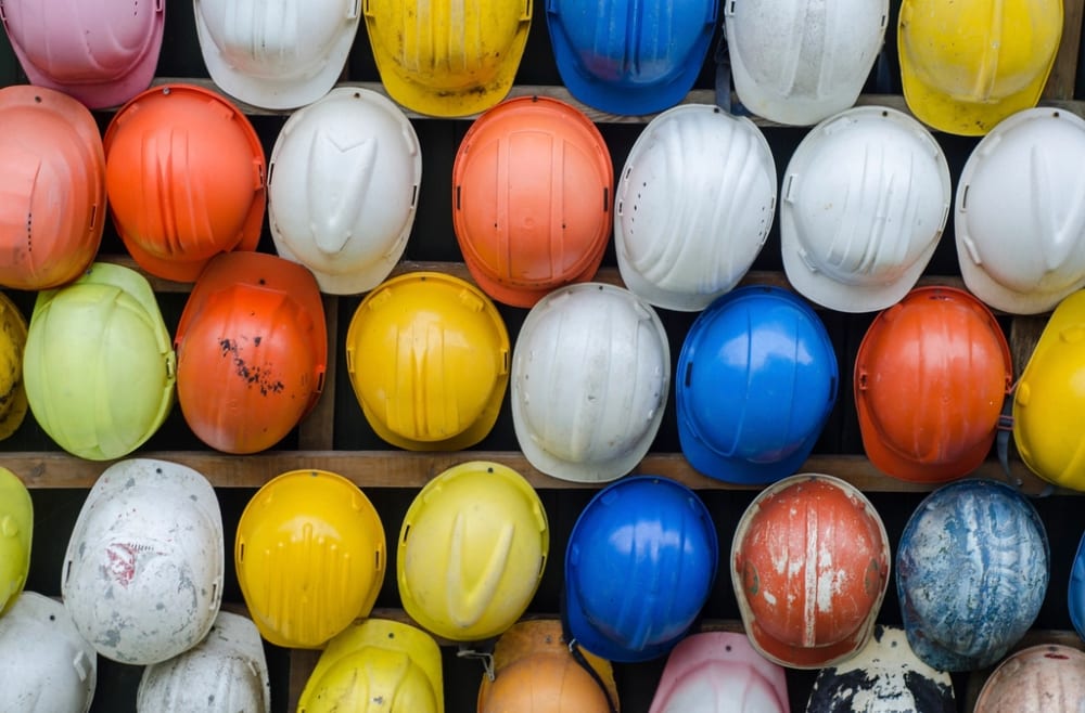 Rows of well-used hard hats hung on racks in yellow, white, orange and blue, scuffed and marked from real use.