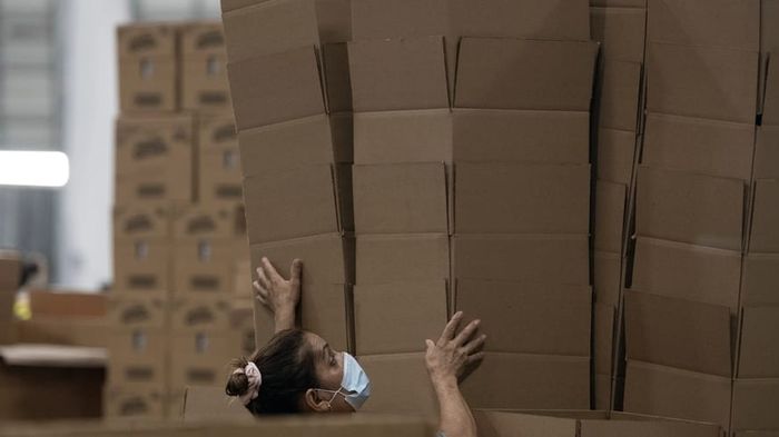 A packing crew filling and checking cartons along a consumer goods line.